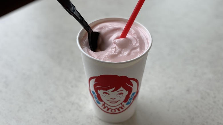 a pink Frosty with spoon and straw
