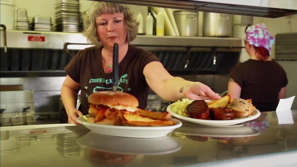 A woman in a restaurant kitchen serves up food