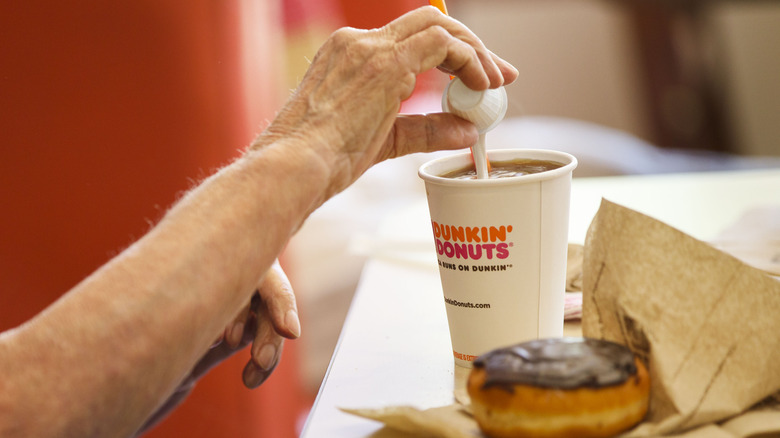 pouring creamer in dunkin donuts coffee