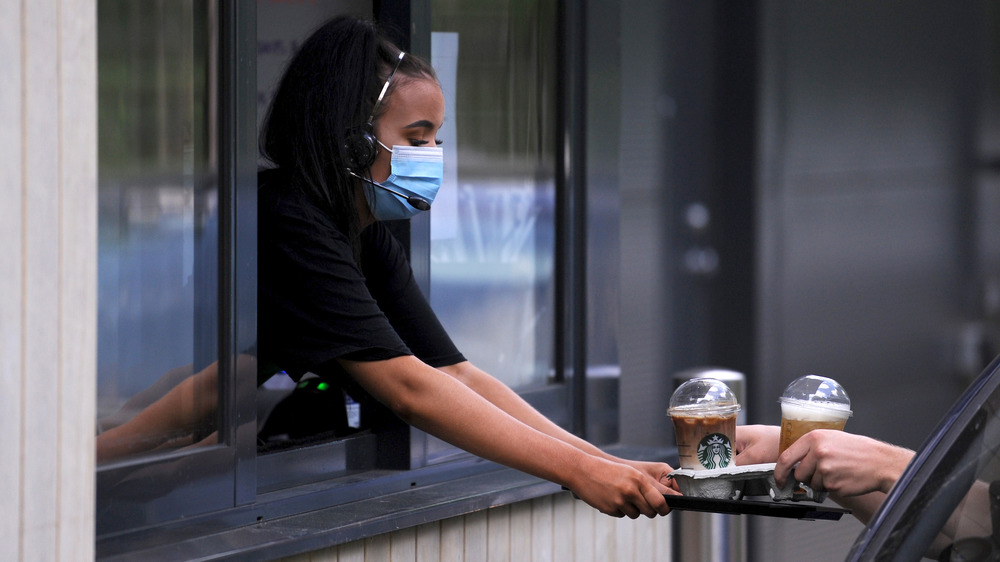 Starbucks worker handing customer drinks