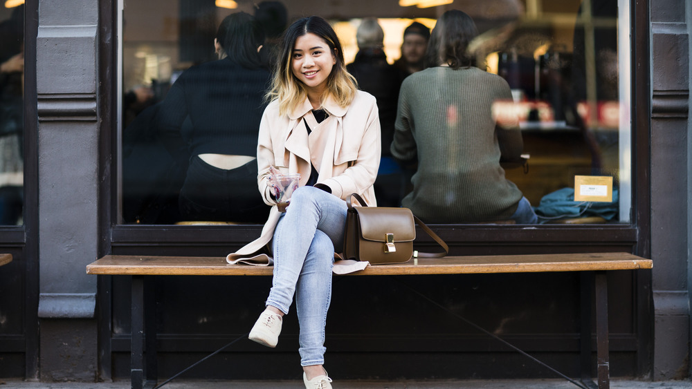 woman in light jeans sitting in front of cafe