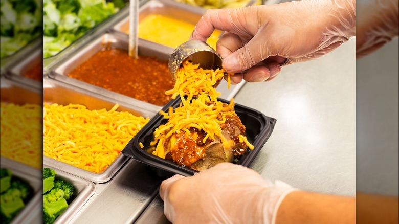 A Wendy's employee dressing a baked potato