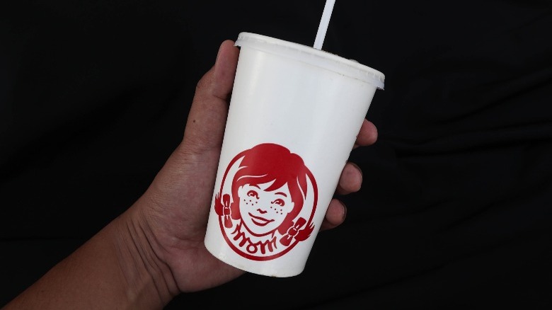 Hand holding Wendy's cup against black background