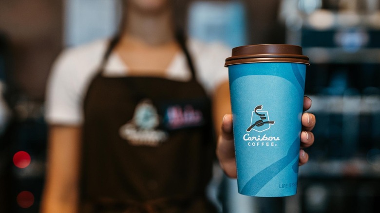 Employee holding Caribou Coffee cup