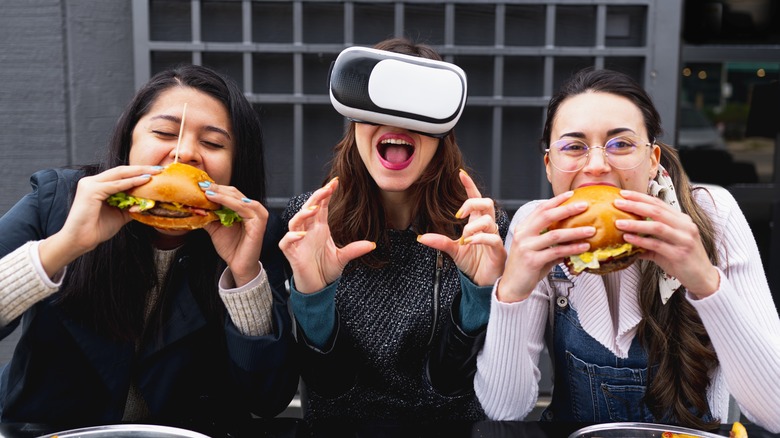 Person with VR glasses between people eating burgers