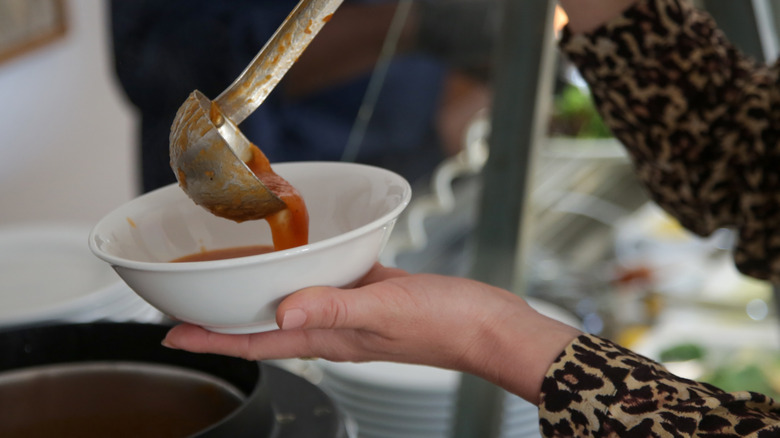 Person serving themself soup at a buffet