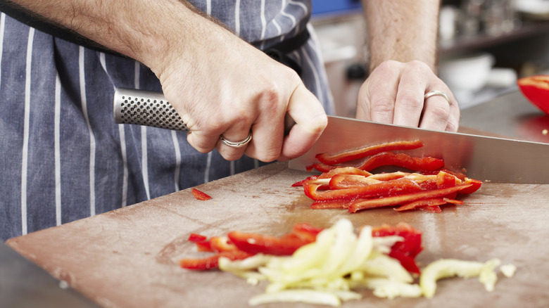 chef uses knife to cut vegetables