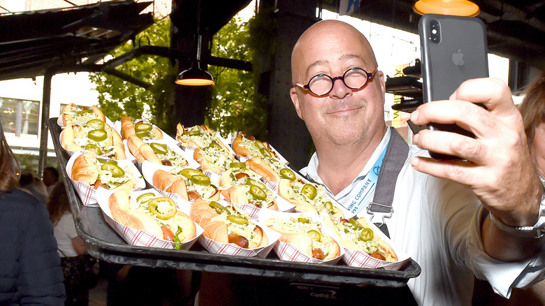 Andrew Zimmern taking selfie with hot dogs