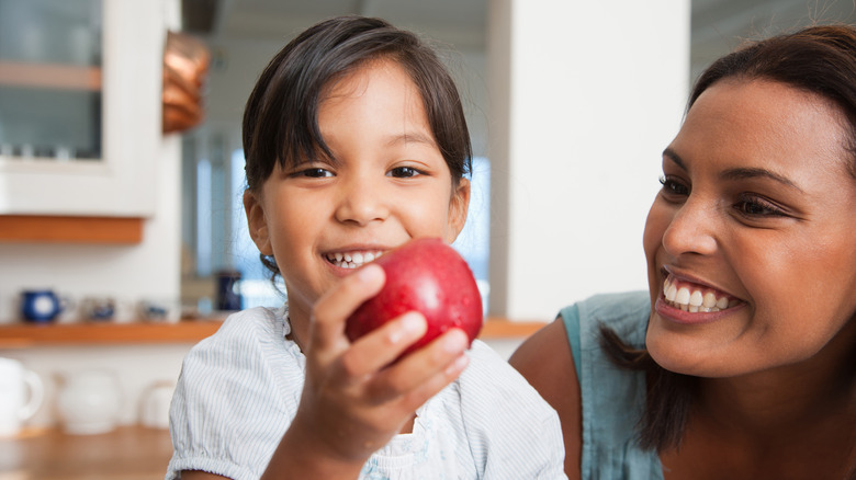 Child holding apple and smiling 