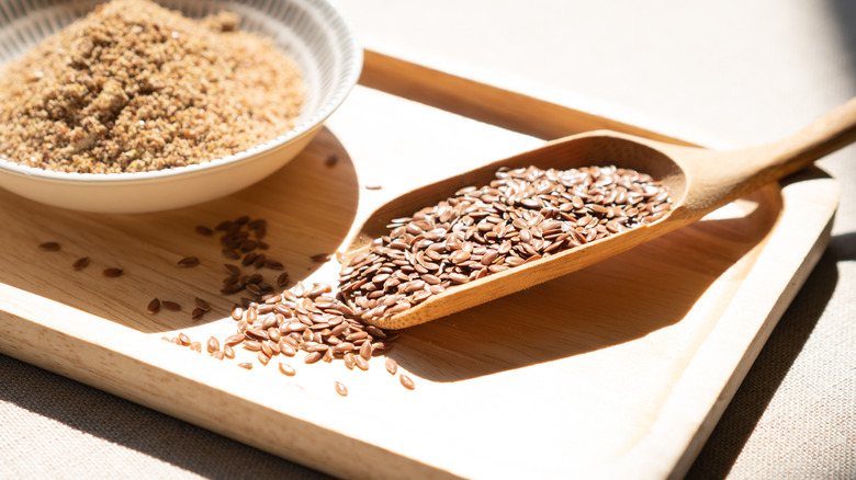 Flaxseeds in wooden scooper next to bowl