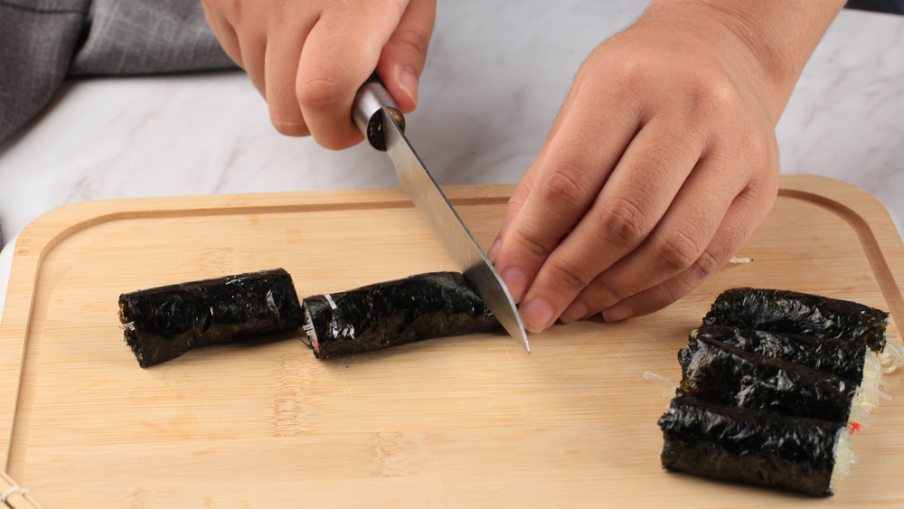 Hands cutting gimmari with knife