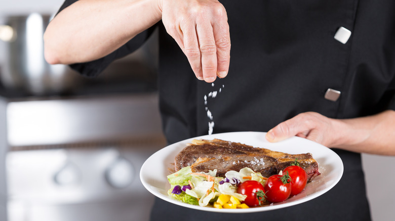 A chef finishes a dish with salt