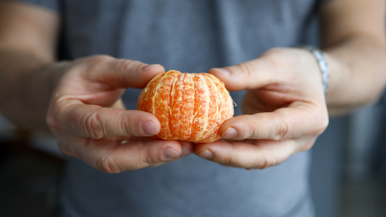 Man holding a peeled mandarin