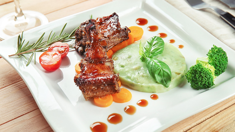 A gourmet plate of food with mushy peas as a side dish