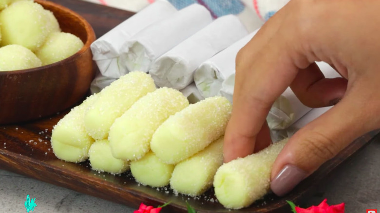 Hand grabbing pastillas de leche from tray