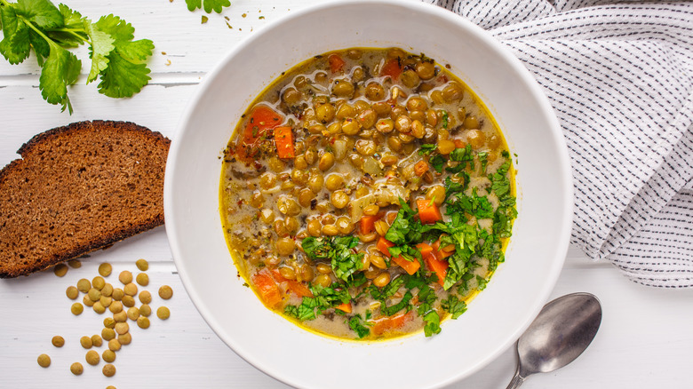 Lentil stew in white bowl next to bread