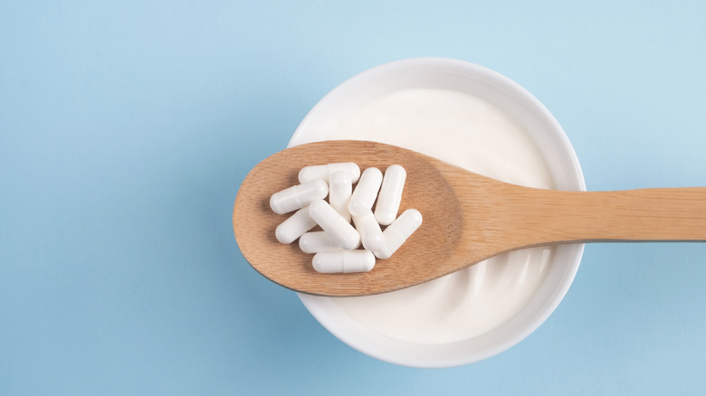 Bowl of yogurt with wooden spoon and supplements