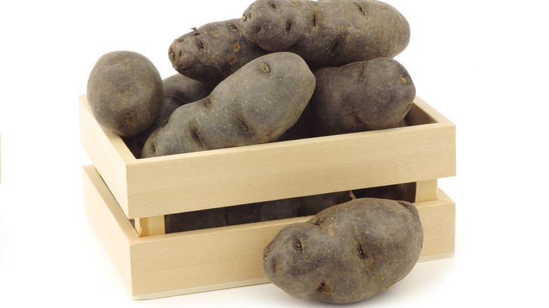 purple potatoes piled in wood crate