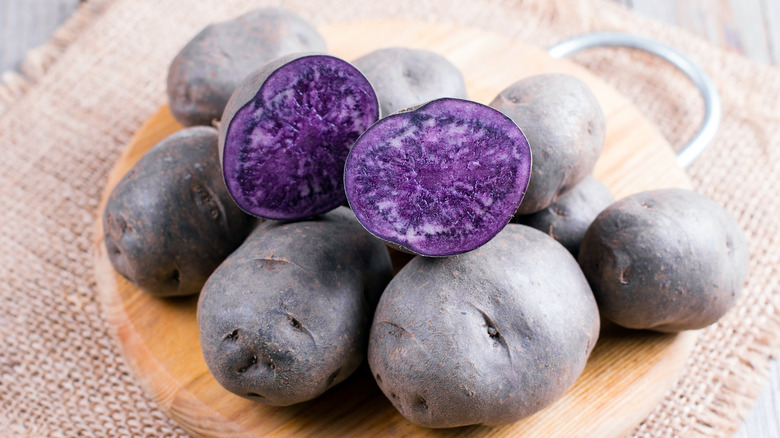 purple potato sliced open on wood board 