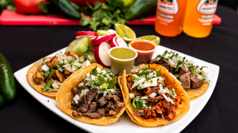 Plate of tacos with salsa, lime wedges, and radishes