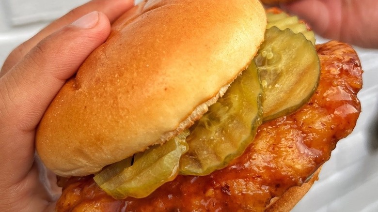 Wingstop Chicken sandwich with pickles held by customer