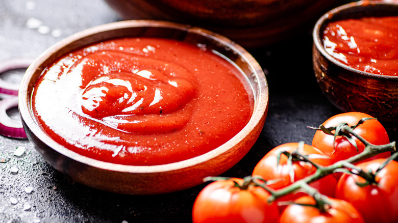 Ketchup in wooden bowl with tomatoes 