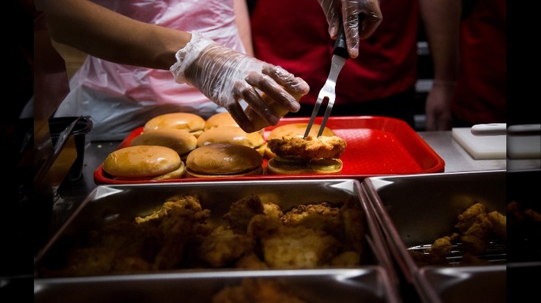 Gloved worker putting together Chick-fil-A sandwiches