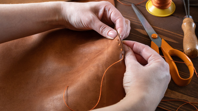 Hands crafting a leather bag