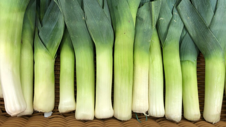 leeks in a row on wooden chopping board 