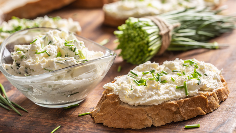cream cheese with chives on wood with bread