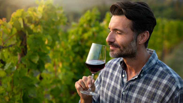 Man taking sniff from wine glass