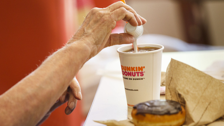 Customer pouring creamer into coffee