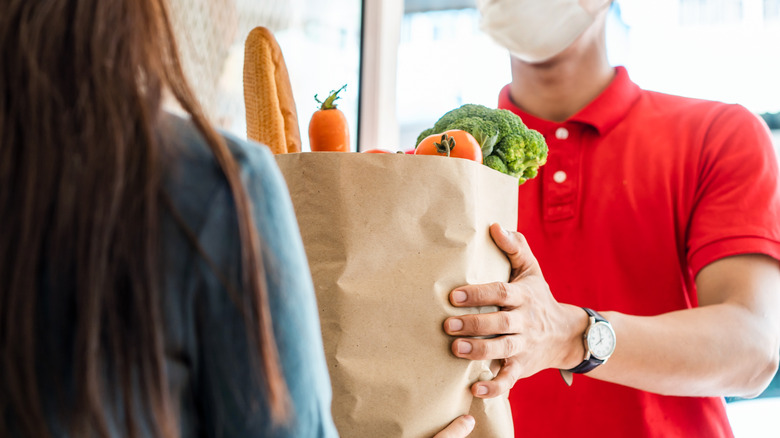 clerk handing person bagged groceries