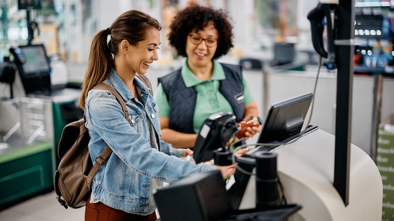 clerk helping self checkout patron