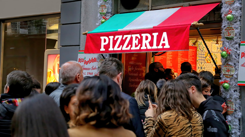 crowd waiting outside pizzeria 