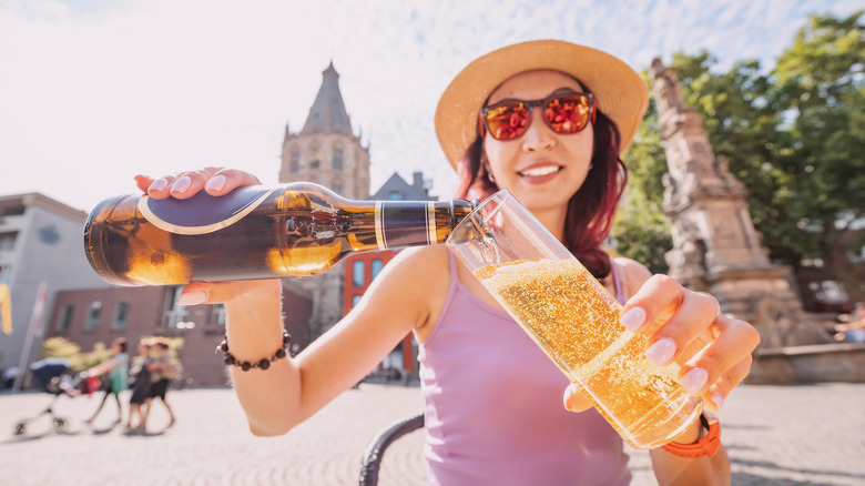 Woman pouring Kölsch beer bottle into traditional Kölsch beer glass