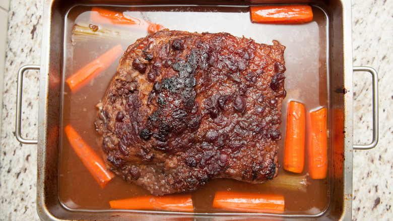 Braised brisket in a baking pan with carrots