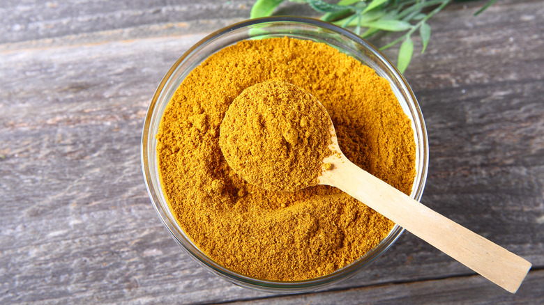 bowl of curry powder with wooden spoon