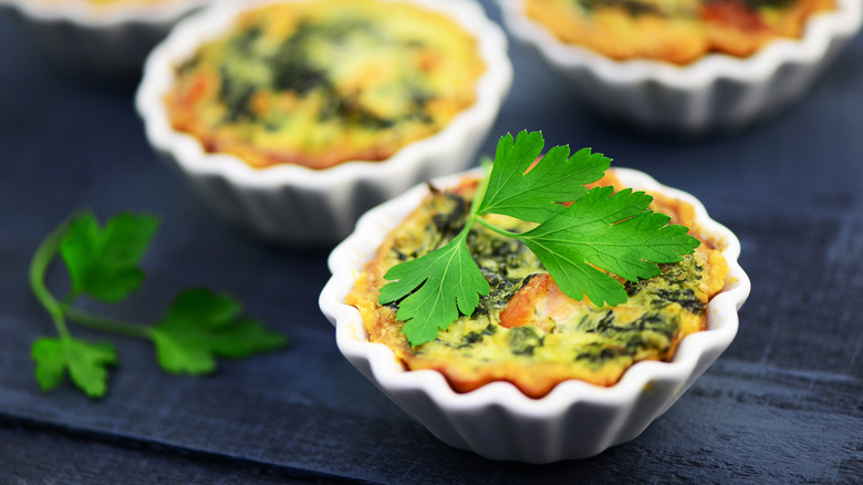 bite-size quiches in white ramekins with parsley leaf