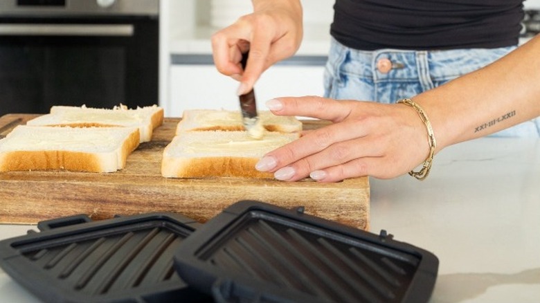 Person buttering toasted sandwich bread