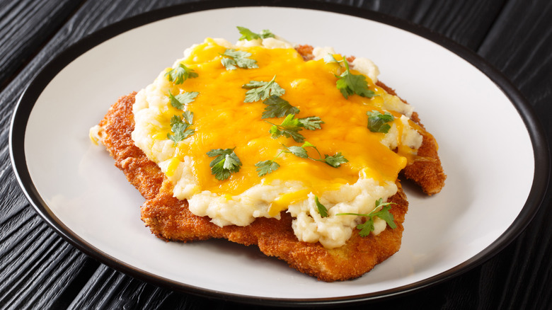 Parmo on white plate over black table