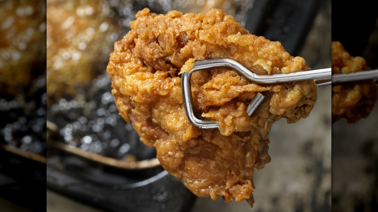 holding chicken fried in oil