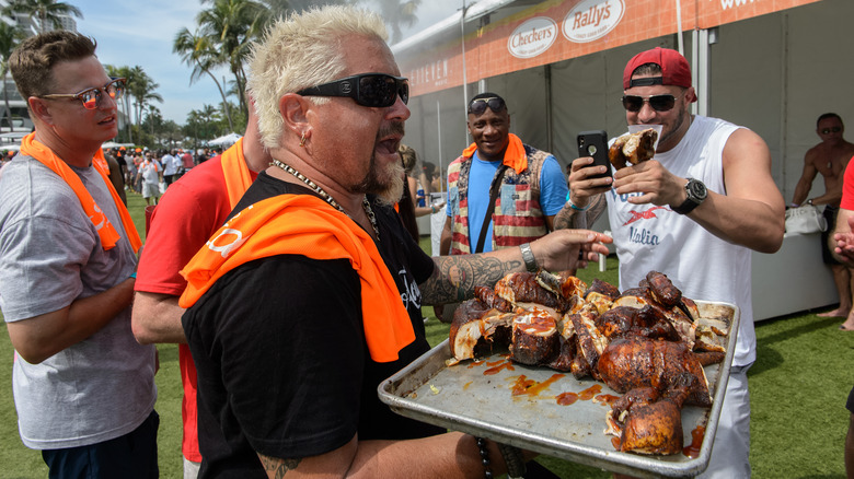 Guy Fieri holding a tray of BBQ