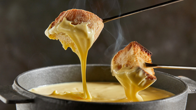 Fondue forks with bread and melted cheese