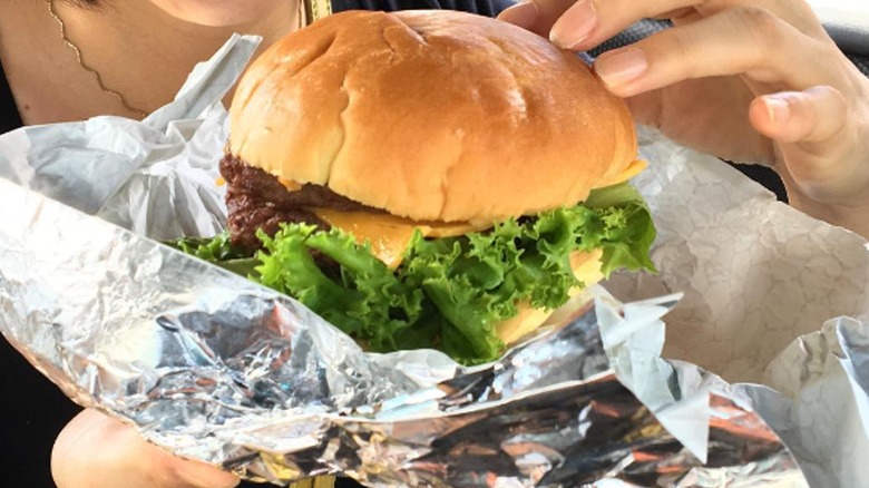 person holding cheeseburger from Costco food court