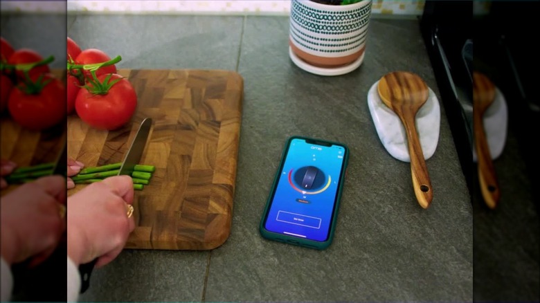 Someone chopping vegetables with Ome app open on phone