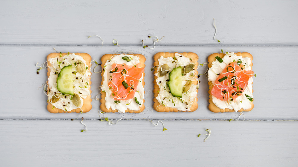 Whole grain crackers with cheese, vegetables, and salmon