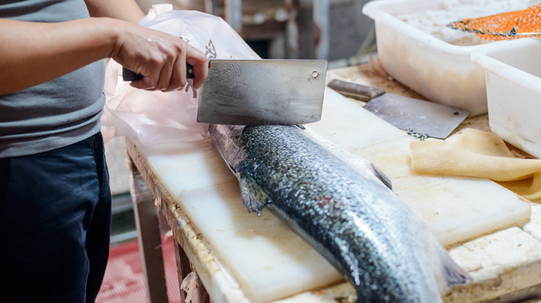 person cutting fish with cleaver