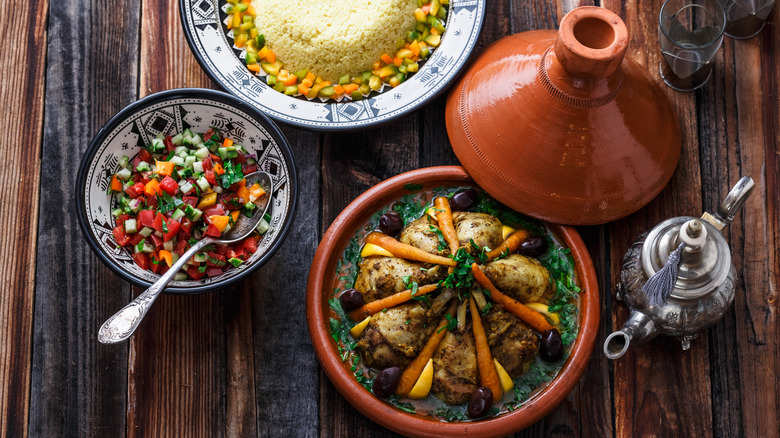 Clay pot with chicken tagine next to bowl of salad