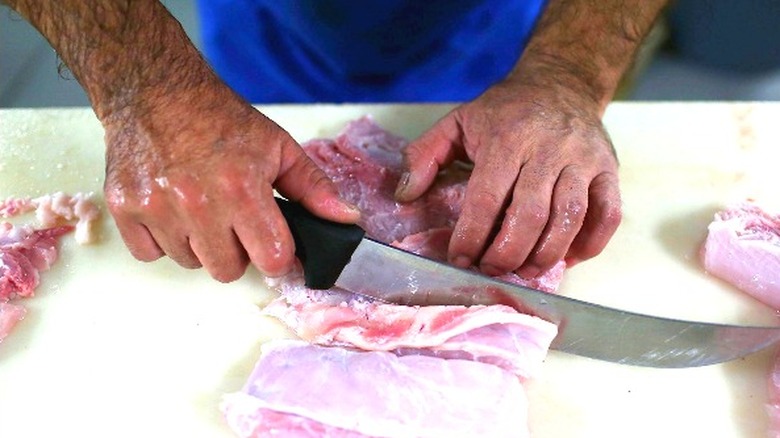 person butchering alligator meat